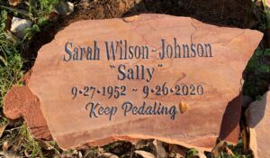 A reddish natural stone grave marker with carved and painted lettering